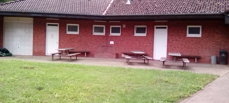Sportplatzhäuschen mit Bänken und Rasen